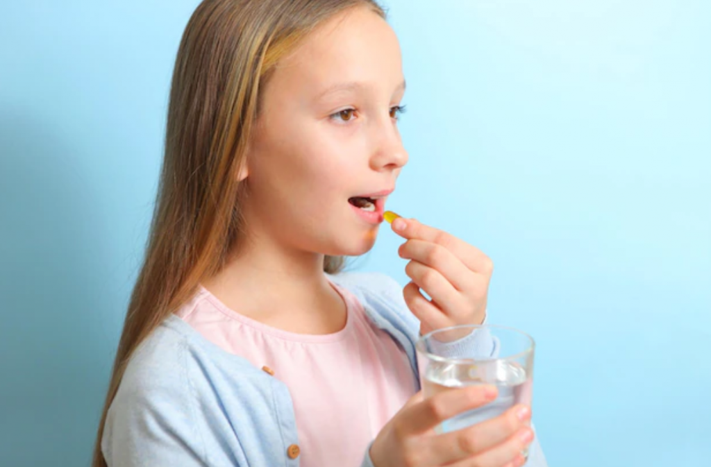 girl taking an omega 3 capsule and a glass of water