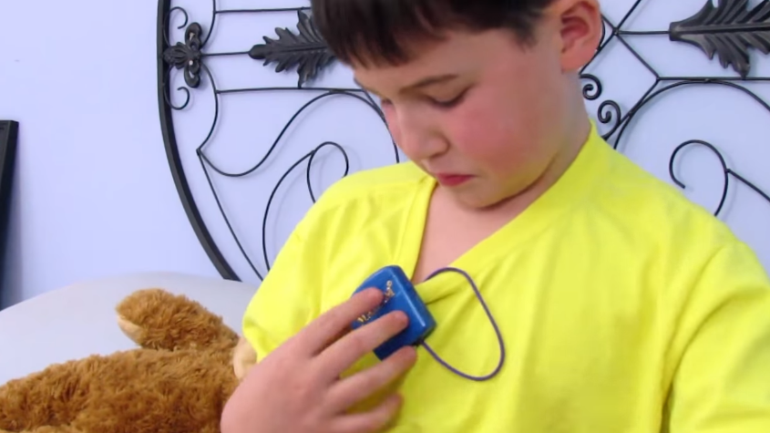 a boy hanging a bed wetting alarm on his shirt collar